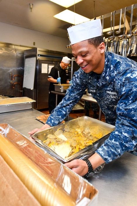 Navy culinary specialist Petty Officer 2nd Class Lawrence Jasper, assigned to Naval Base Kitsap's Trident Inn Galley in Silverdale, Wash., wraps potatoes in plastic-wrap for lunch, May 2, 2017. Navy photo by Petty Officer 3rd Class Charles D. Gaddis IV
