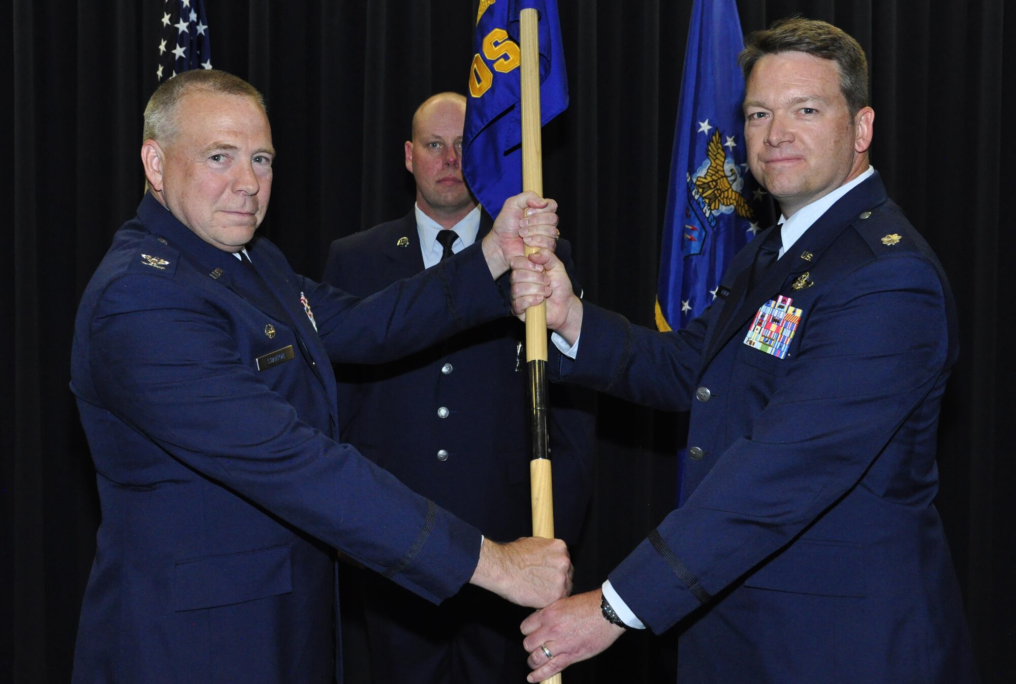 Col. Robert Stanton, left, the 302nd Operations Group commander, passes the  302nd Operations Support Squadron guidon to Lt. Col. Ryan Tanton, right, who assumed command of the squadron during a change of command ceremony, April 1, 2017, at Peterson Air Force Base, Colo. Tanton takes command of the 302nd OSS after serving as the 731st Airlift Squadron chief navigator.  (U.S. Air Force photo/Staff Sgt. Frank Casciotta)