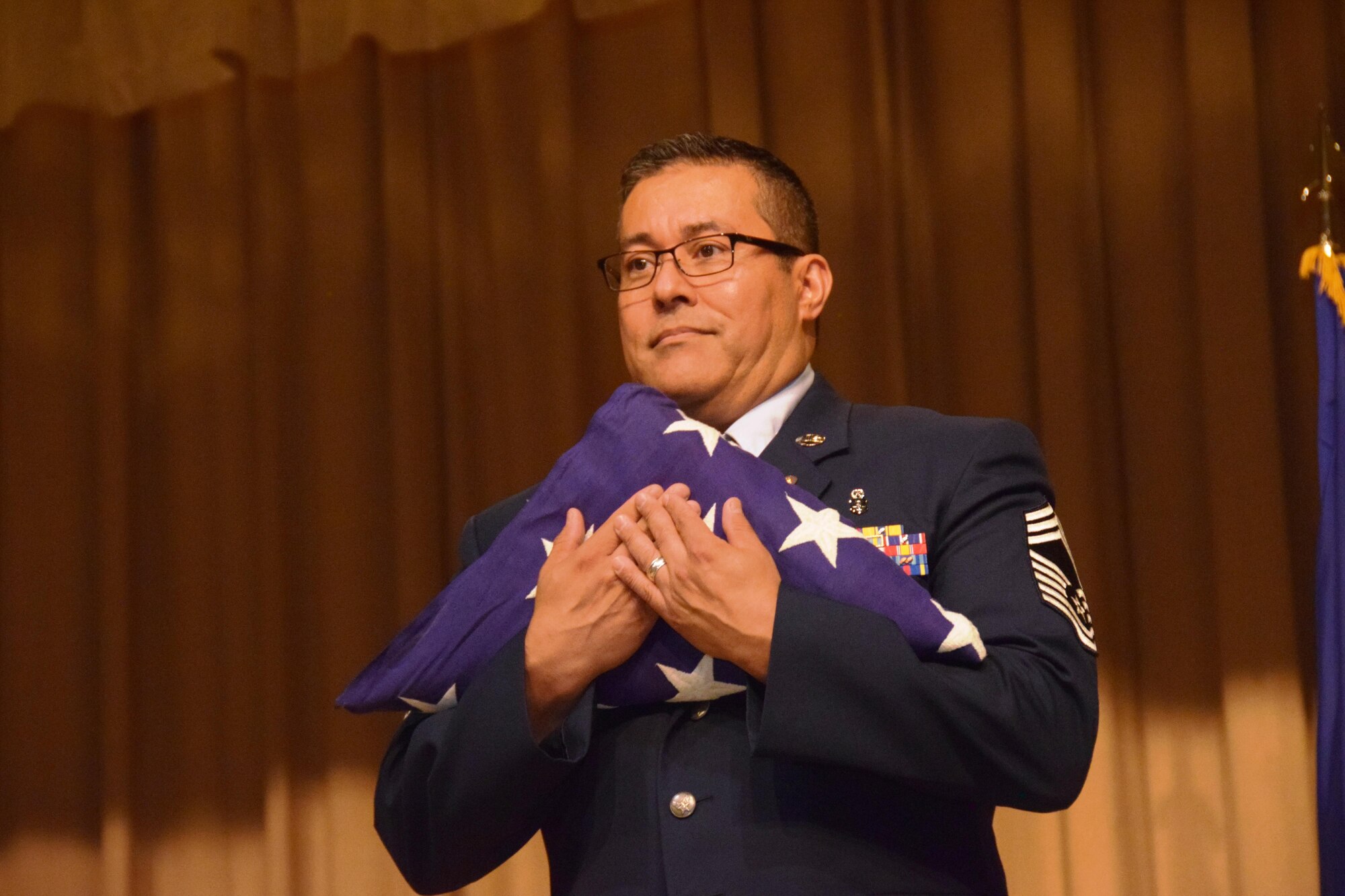 Chief Master Sgt. Christopher E. Florez holds the United States flag presented to him during his retirement in the Wilford Hall Auditorium at Joint Base San Antonio-Lackland, Texas on May. 7, 2017. The chief’s career spanned over 30 years. He enlisted in the Air Force in December 1986 and spent his entire active duty career at Wilford Hall before joining the Alamo Wing in 1998. (U.S. Air Force photo by Tech. Sgt. Carlos J. Trevino)