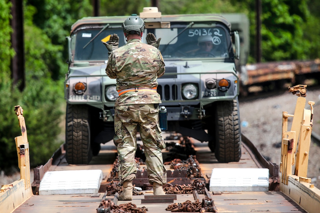 A New Jersey Army National Guardsman uses hand signals to direct a vehicle onto a rail car at Morrisville Yard, Pa., May 2, 2017. Air National Guard photo by Master Sgt. Matt Hecht