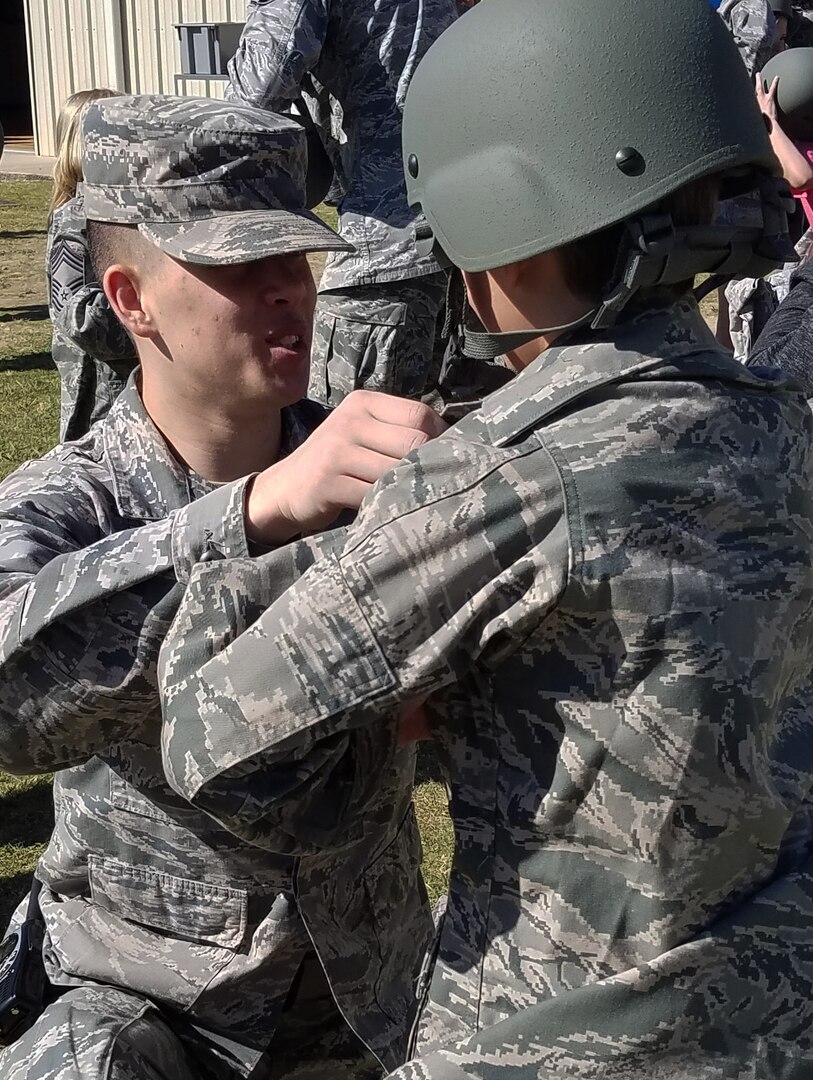 Airmen Ethan McFarland, 502nd Logistics Readiness Squadron logistics planner, assists a fourth-grade student with donning an Airman Battle Uniform top during a simulated deployment process as part of Operation FLAGS May 5, 2017 on the Randolph Elementary School campus at JBSA-Randolph, Texas. Operation FLAGS, which stands for Families Learning About Global Support, is a means of educating families about what their loved ones go through when they deploy.