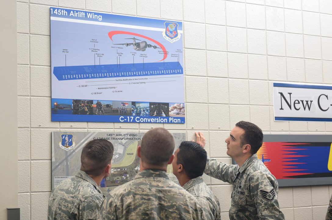 Members of the North Carolina Air National Guard (NCANG) browse the information boards and review the newly unveiled C-17 Globemaster III aircraft tail flash in the dining facility at the NCANG Base, Charlotte Douglas International Airport, May 6, 2017. The tail flash is an integral part of establishing the brand of the NCANG. Every detail from the colors, to the length of the sabre, and the bold print symbolize the importance of new mission that will be carried out by the airmen and C-17 Globemaster III aircraft. (U.S. Air National Guard photo by Staff. Sgt. Laura J. Montgomery)