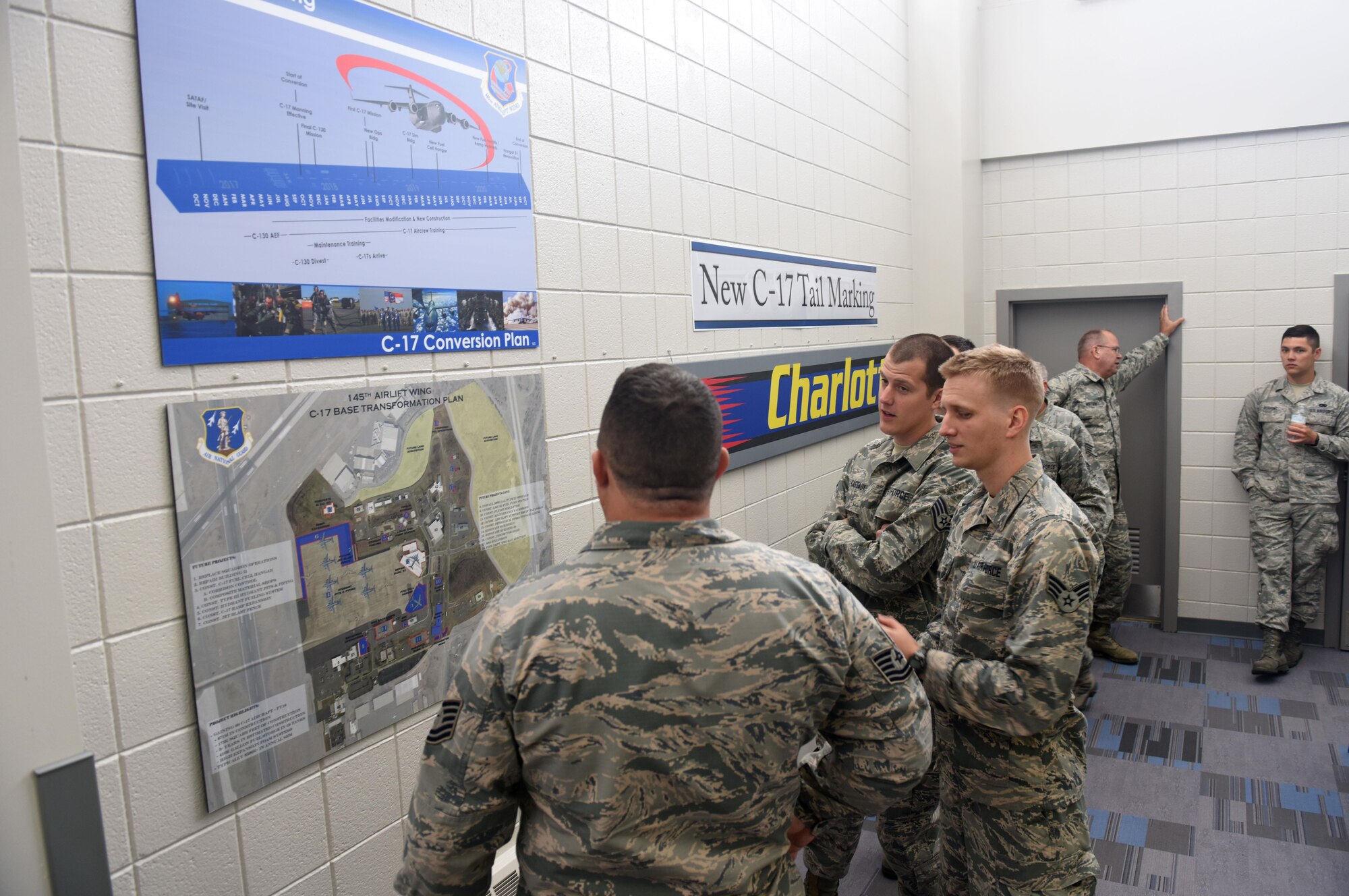 Members of the North Carolina Air National Guard (NCANG) browse the information boards and review the newly unveiled C-17 Globemaster III aircraft tail flash in the dining facility at the NCANG Base, Charlotte Douglas International Airport, May 6, 2017. The tail flash is an integral part of establishing the brand of the NCANG. Every detail from the colors, to the length of the sabre, and the bold print symbolize the importance of new mission that will be carried out by the airmen and C-17 Globemaster III aircraft. (U.S. Air National Guard photo by Staff. Sgt. Laura J. Montgomery)