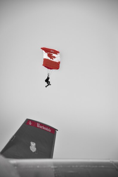 A member of the Canadian Armed Forces Skyhawks parachute demonstration team sails by the vertical stabilizer of a B-52H Stratofortress while preparing to land at the 2017 Defenders of Liberty Airshow on Barksdale Air Force Base, La., May 7.  The team repeatedly jumped out of a C-17 Globemaster III, falling thousands of feet through the air while making a controlled descent to the flightline, where more than 100,000 people greeted them with cheers and applause. (U.S. Air Force photo illustration//Staff Sgt. Joseph Raatz)