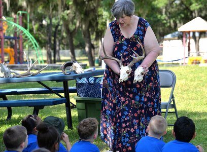 Cathy Kropp, U.S. Army Environmental Command environmental public affairs specialist, shows male and female deer skulls to kindergarten students from Fort Sam Houston Elementary School during a field trip April 26 in Salado Creek Park at Joint Base San Antonio-Fort Sam Houston. The field trip gave the schoolchildren the opportunity to learn about nature and wildlife through various activities set up at seven stations throughout the park.