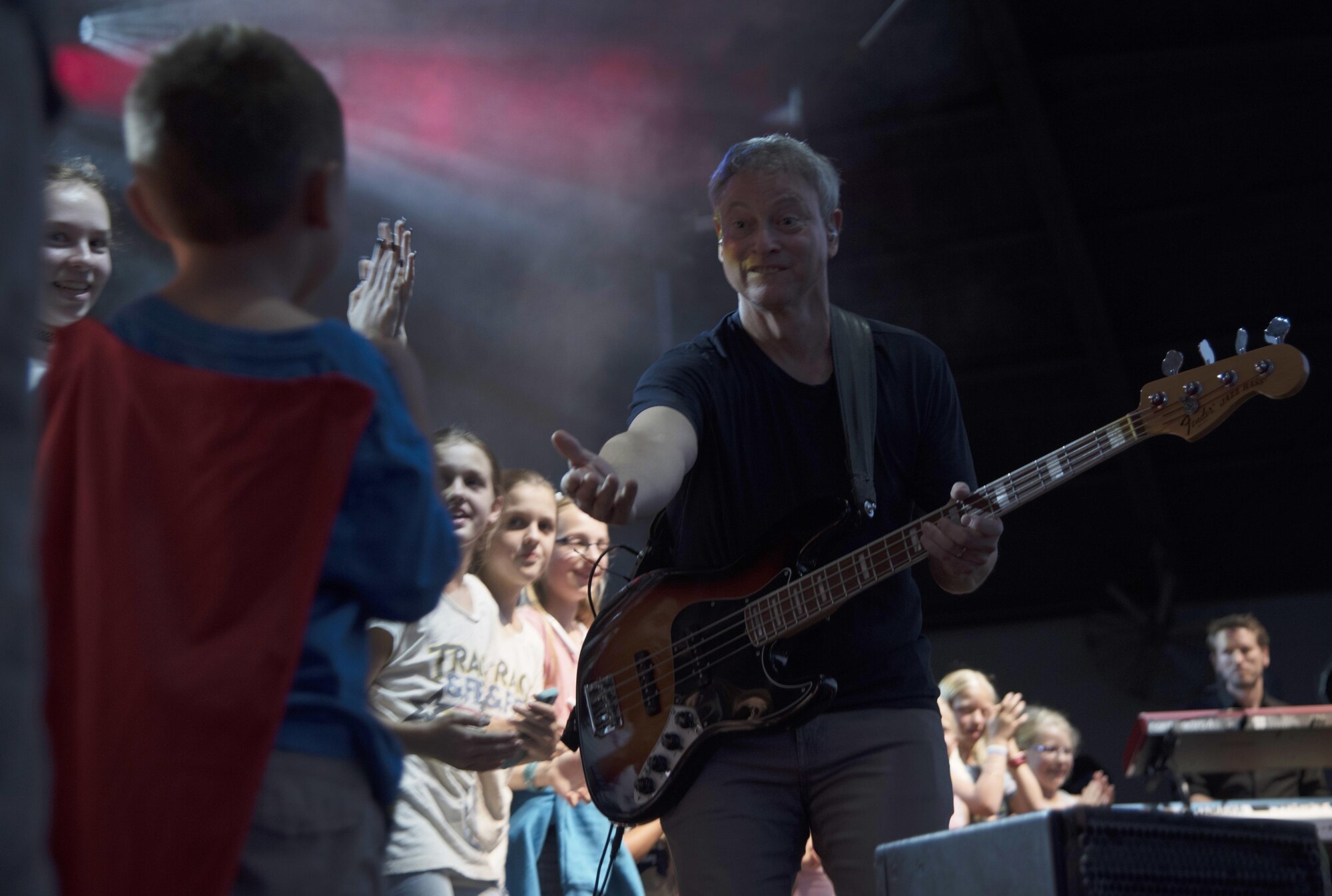 Gary Sinise, the bassist for the Lt. Dan Band, encourages a boy to join the stage during a concert at MacDill Air Force Base, Fla., April 29, 2017. The band invited Team MacDill youth on stage to sing along during their performance. (U.S. Air Force photo by Airman 1st Class Adam R. Shanks)