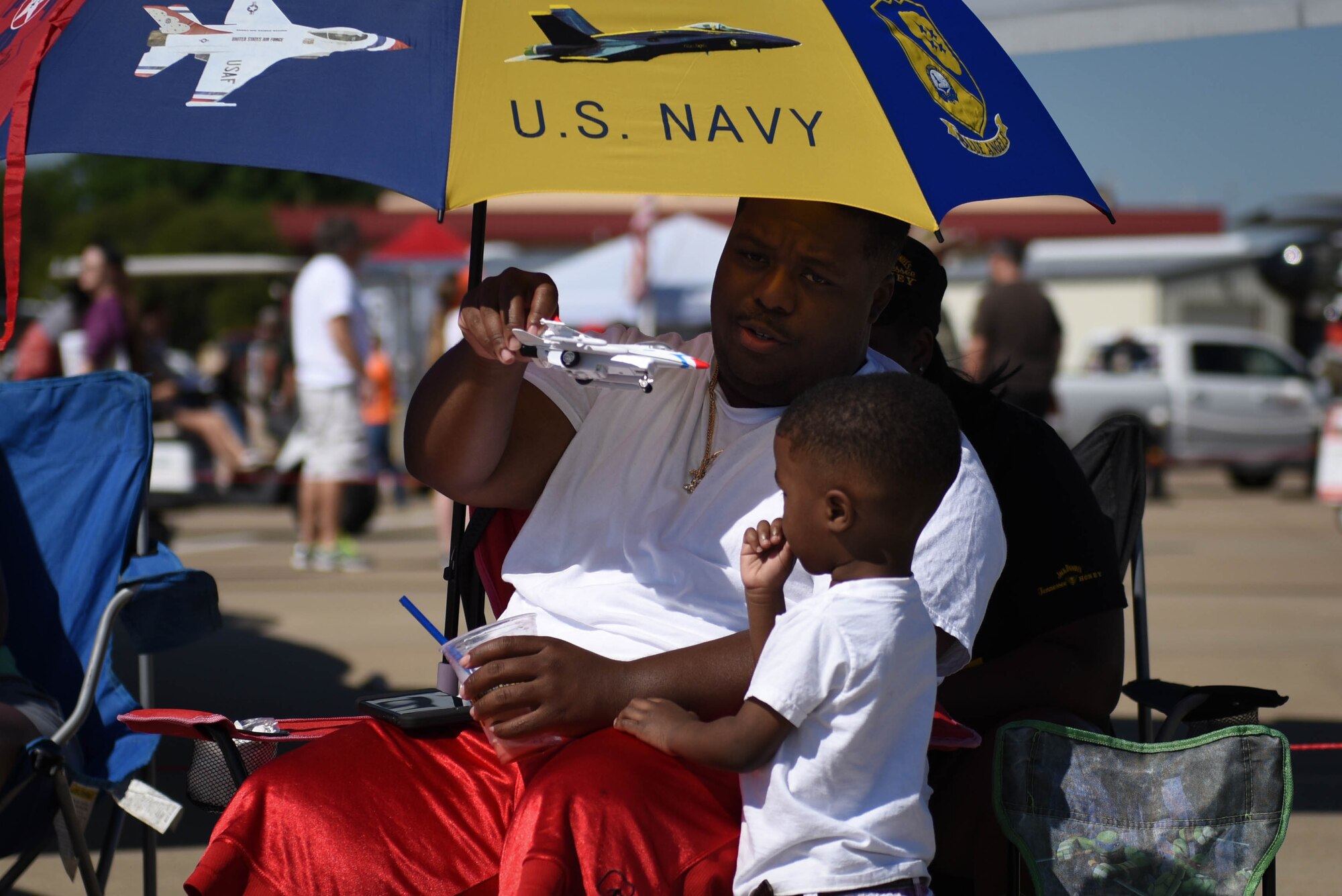 A man plays with a toy airplane with a child at Barksdale Air Force Base, La., May 7, 2017. Held for the first time in 1933, the Barksdale Air Force Base air show is a full weekend of military and civilian aircraft and performances and displays. (U.S. Air Force photo/Airman 1st Class Stuart Bright)