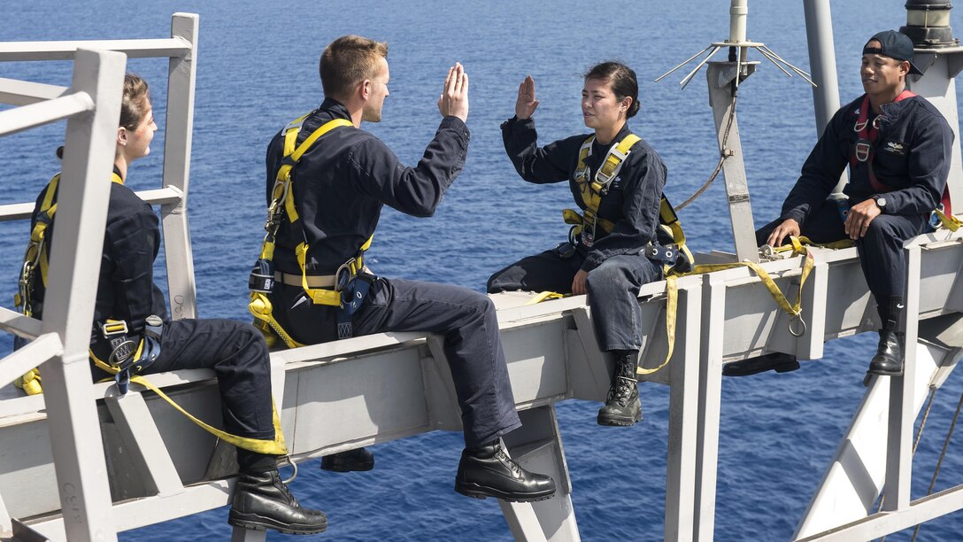 Navy Lt. Cmdr. Ben McCarty, second from left, re-enlists Petty Officer 2nd Class Nikki Duffy on the yardarm of the USS Ross in the Mediterranean Sea, May 3, 2017. The Ross is supporting U.S. national security interests in Europe and Africa. Duffy is an information systems technician. Navy photo by Petty Officer 3rd Class Robert S. Price
