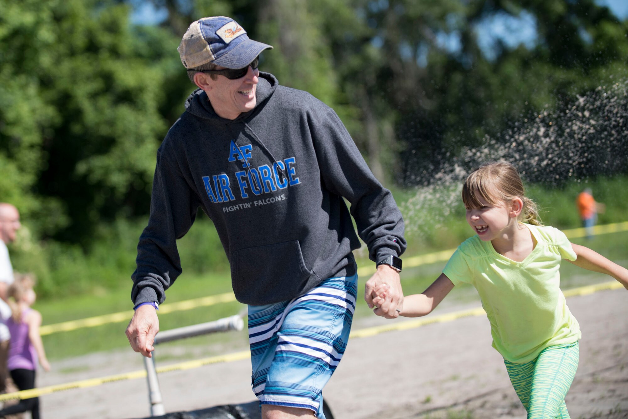 Col. Thomas Kunkel, 23d Wing commander, and his daughter, Avery, run through sprinklers during the annual Moody Mud Run, May 6, 2017, in Ray City, Ga. The Fourth Annual Moody Mud consisted of both adult and child course that challenged more than 600 participants with obstacles over 4.2 miles. (U.S. Air Force photo by Airman 1st Class Daniel Snider)