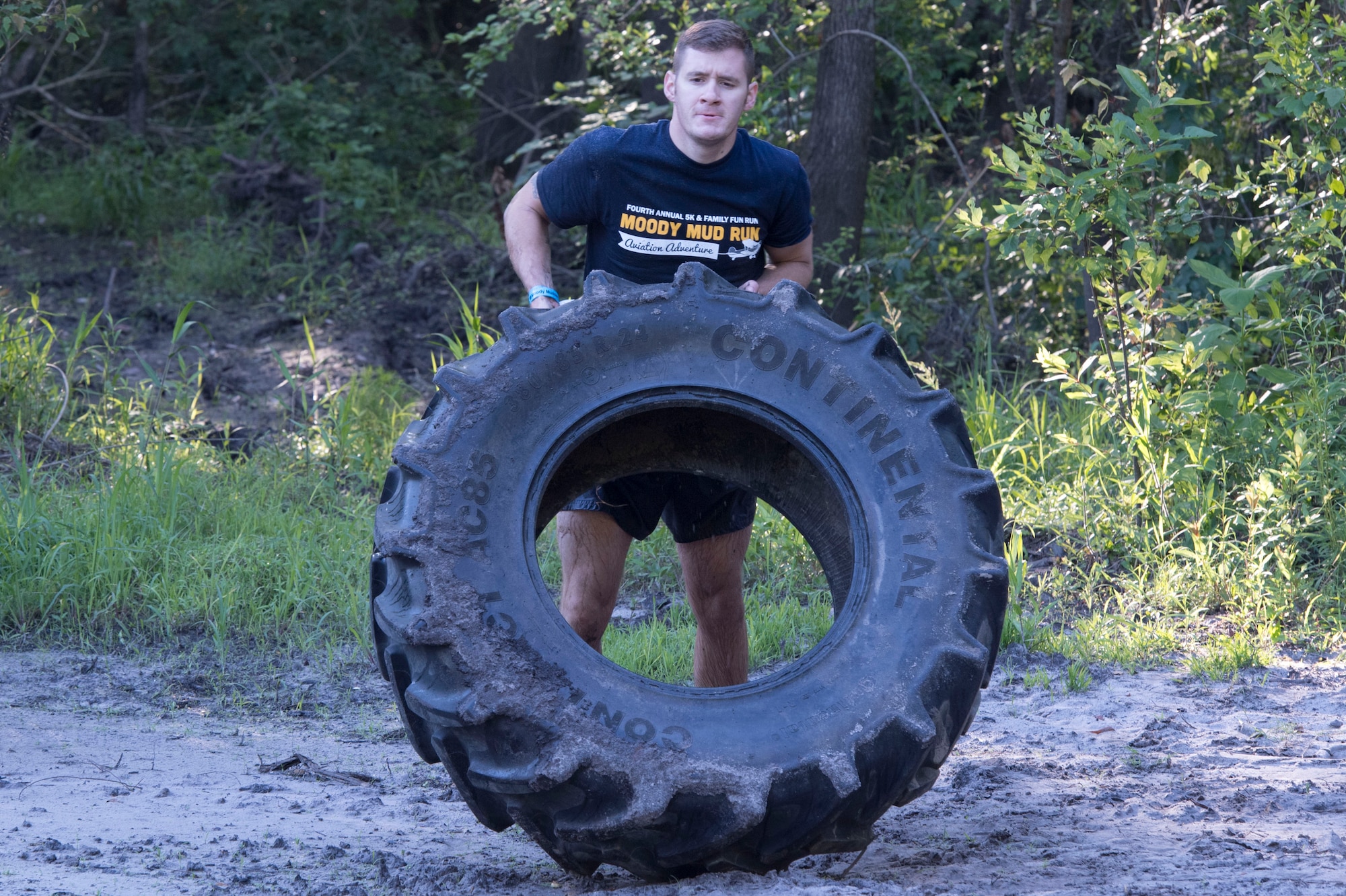 A Moody Mud Run participant flips a tire as part of an obstacle during the 4.2 mile race, May 6, 2017, in Ray City, Ga. The Fourth Annual Moody Mud consisted of both adult and child course that challenged more than 600 participants with obstacles over 4.2 miles. (U.S. Air Force photo by Staff Sgt. Eric Summers Jr.)