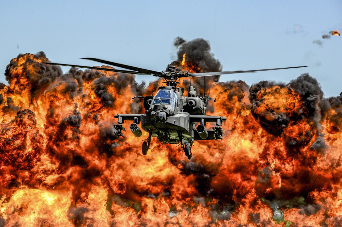 An AH-64D Apache attack helicopter flies in front of a wall of fire during the South Carolina National Guard Air and Ground Expo at McEntire Joint National Guard Base, S.C., May 6, 2017. The expo showcases South Carolina National Guard airmen and soldiers. Air National Guard photo by Tech. Sgt. Jorge Intriago