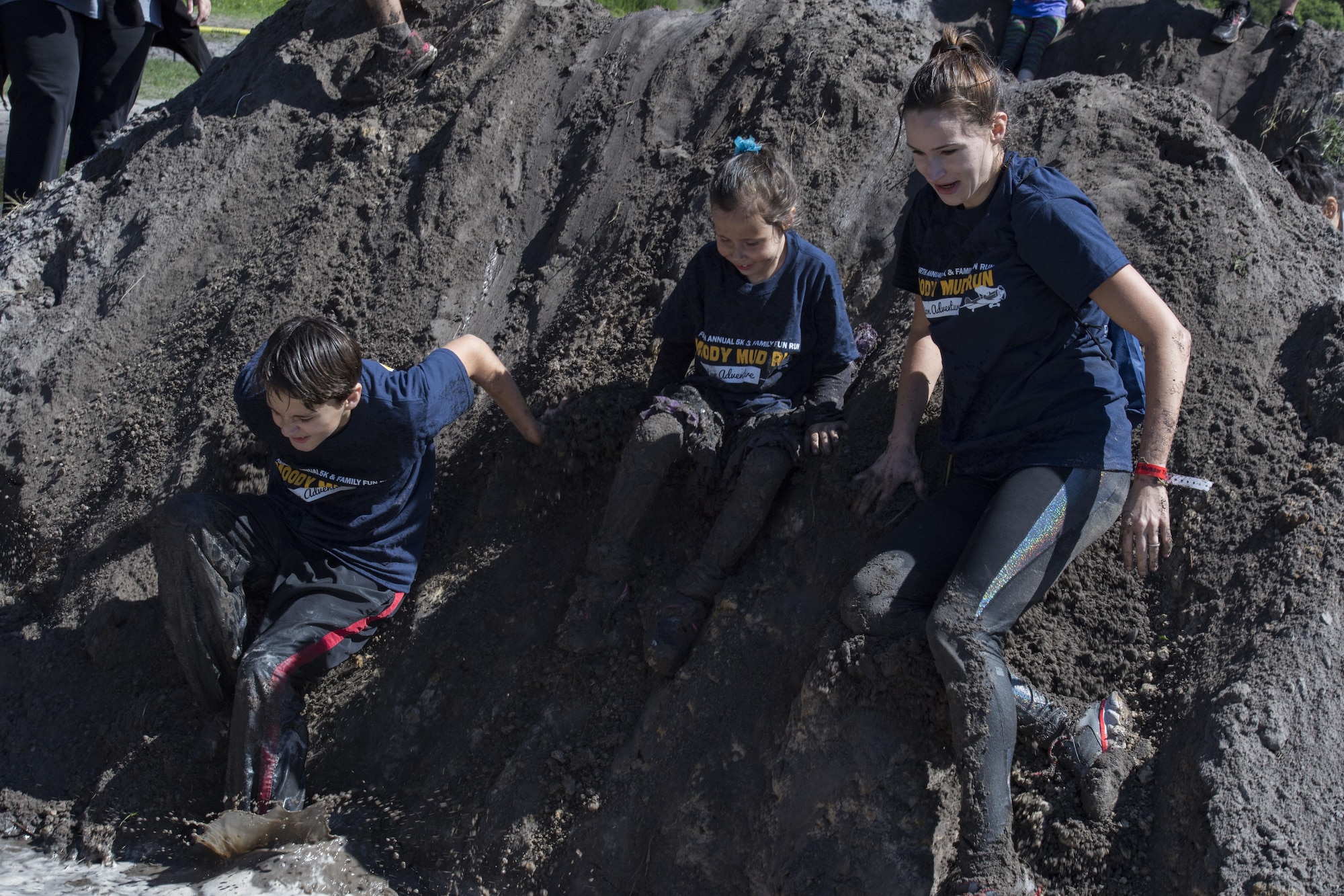 A family slides down a hill during the child’s course of the Moody Mud Run, May 6, 2017, in Ray City, Ga. The Fourth Annual Moody Mud consisted of both adult and child course that challenged more than 600 participants with obstacles over 4.2 miles. (U.S. Air Force photo by Staff Sgt. Eric Summers Jr.)