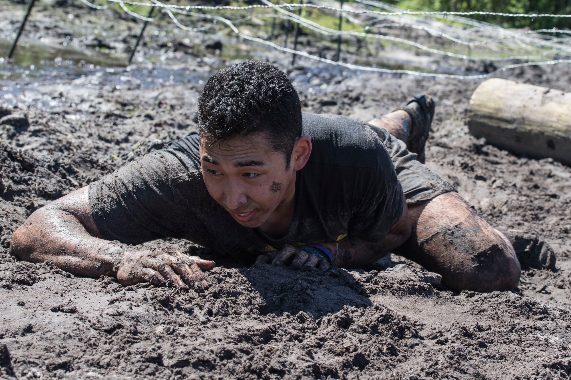 A Moody Mud Run participant low-crawls under barbed wire during the Moody Mud Run, May 6, 2017, in Ray City, Ga. The Fourth Annual Moody Mud consisted of both adult and child course that challenged more than 600 participants with obstacles over 4.2 miles. (U.S. Air Force photo by Staff Sgt. Eric Summers Jr.)