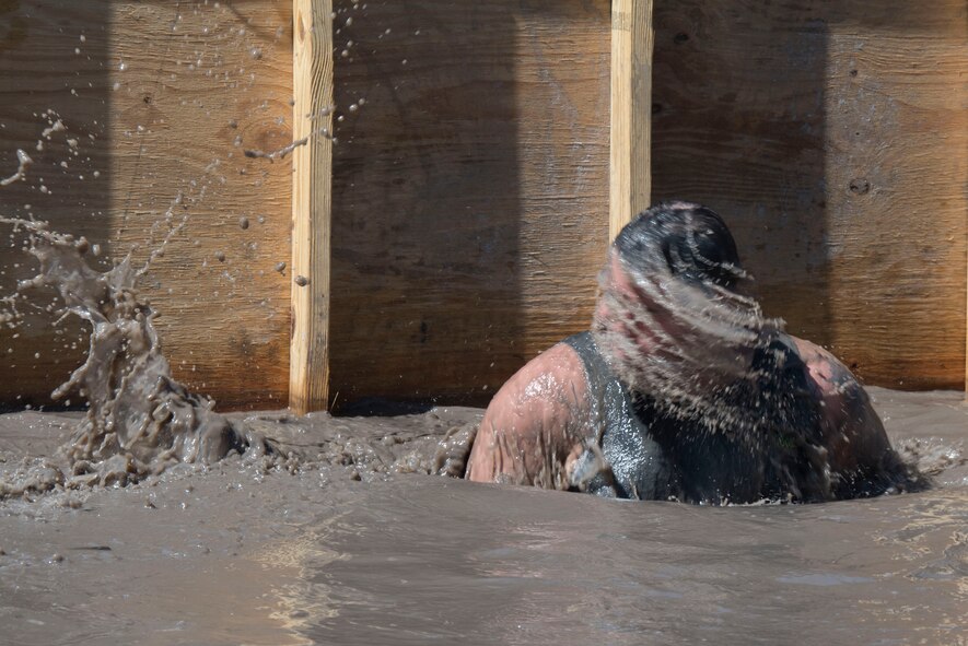 A Moody Mud Run participant rises from muddy water after going underneath a wooden stand May 6, 2017, in Ray City, Ga. The Fourth Annual Moody Mud consisted of both adult and child course that challenged more than 600 participants with obstacles over 4.2 miles. (U.S. Air Force photo by Staff Sgt. Eric Summers Jr.)