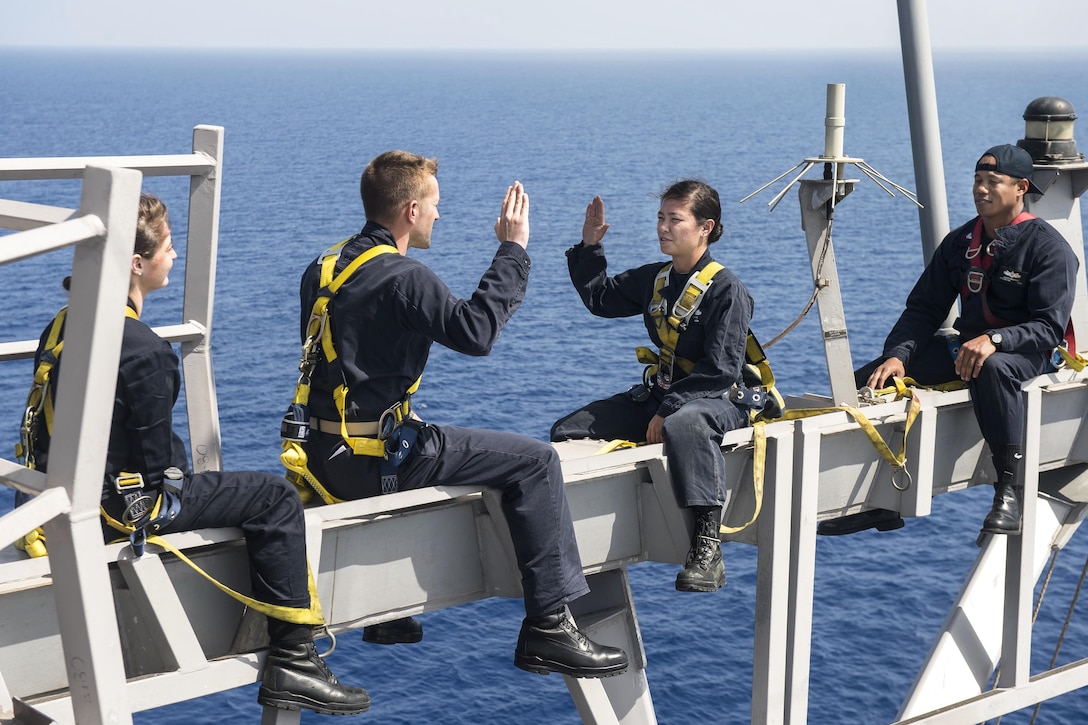 Navy Lt. Cmdr. Ben McCarty, second from left, re-enlists Petty Officer 2nd Class Nikki Duffy on the yardarm of the USS Ross in the Mediterranean Sea, May 3, 2017. The Ross is supporting U.S. national security interests in Europe and Africa. Duffy is an information systems technician. Navy photo by Petty Officer 3rd Class Robert S. Price
