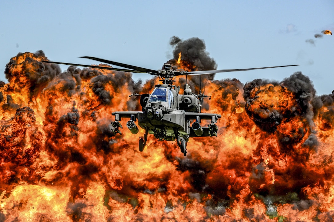 An AH-64D Apache attack helicopter flies in front of a wall of fire during the South Carolina National Guard Air and Ground Expo at McEntire Joint National Guard Base, S.C., May 6, 2017. The expo showcases South Carolina National Guard airmen and soldiers. Air National Guard photo by Tech. Sgt. Jorge Intriago