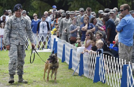 U.S. Air Force Senior Airman Trey Weston, 628th Security Forces Squadron military working dog handler, and Ari, MWD, greet a crowd after performing a demonstration during a base picnic at the Air Base Picnic Grounds May 5, 2017, at Joint Base Charleston, S.C. Attendees were provided free meals and were able to participate in various activities including face painting, wall rock climbing, live music and a Military Working Dog demonstration.