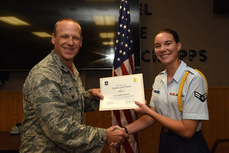 U.S. Air Force Lt. Col. Steven Watts, 17th Training Group deputy commander, presents the 312th Training Squadron Student of the Month award for April 2017 to Airman 1st Class Claire Newman, 312th TRS student, in Brandenburg Hall on Goodfellow Air Force Base, Texas, May 5, 2017. (U.S. Air Force photo by Airman 1st Class Caelynn Ferguson/Released)