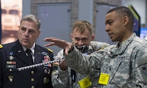Capt. Brent Chapman (right) and Capt. Frederick "Erick" Waage (center) show Gen. Milley (left) their cyber "maker" creation of a prototype cyber "rifle" which allows them to disable drones from a distance.