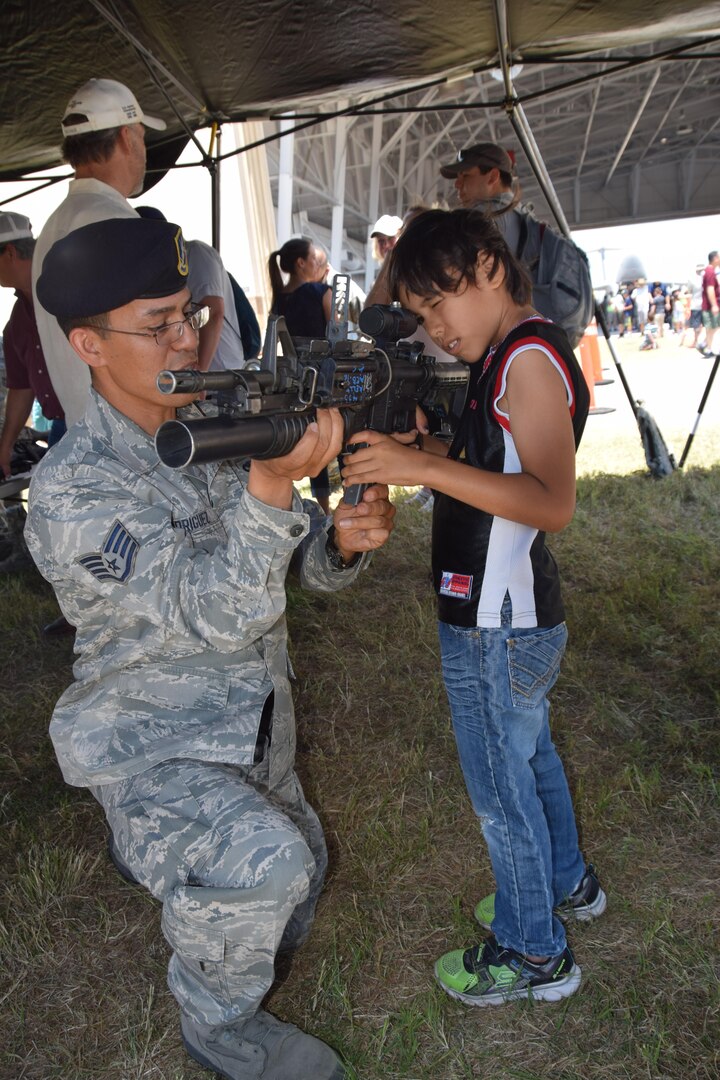 Staff Sgt. Pedro Rodriguez, 433rd Security Forces Squadron, explains how a M-4 rifle and grenade launcher operates to Daniel Mifsud during the 433rd Airlift Wing Family Day May 7, 2017 at Joint Base San Antonio-Lackland, Texas.   (U.S. Air Force photo by Tech. Sgt. Carlos J. Trevino)