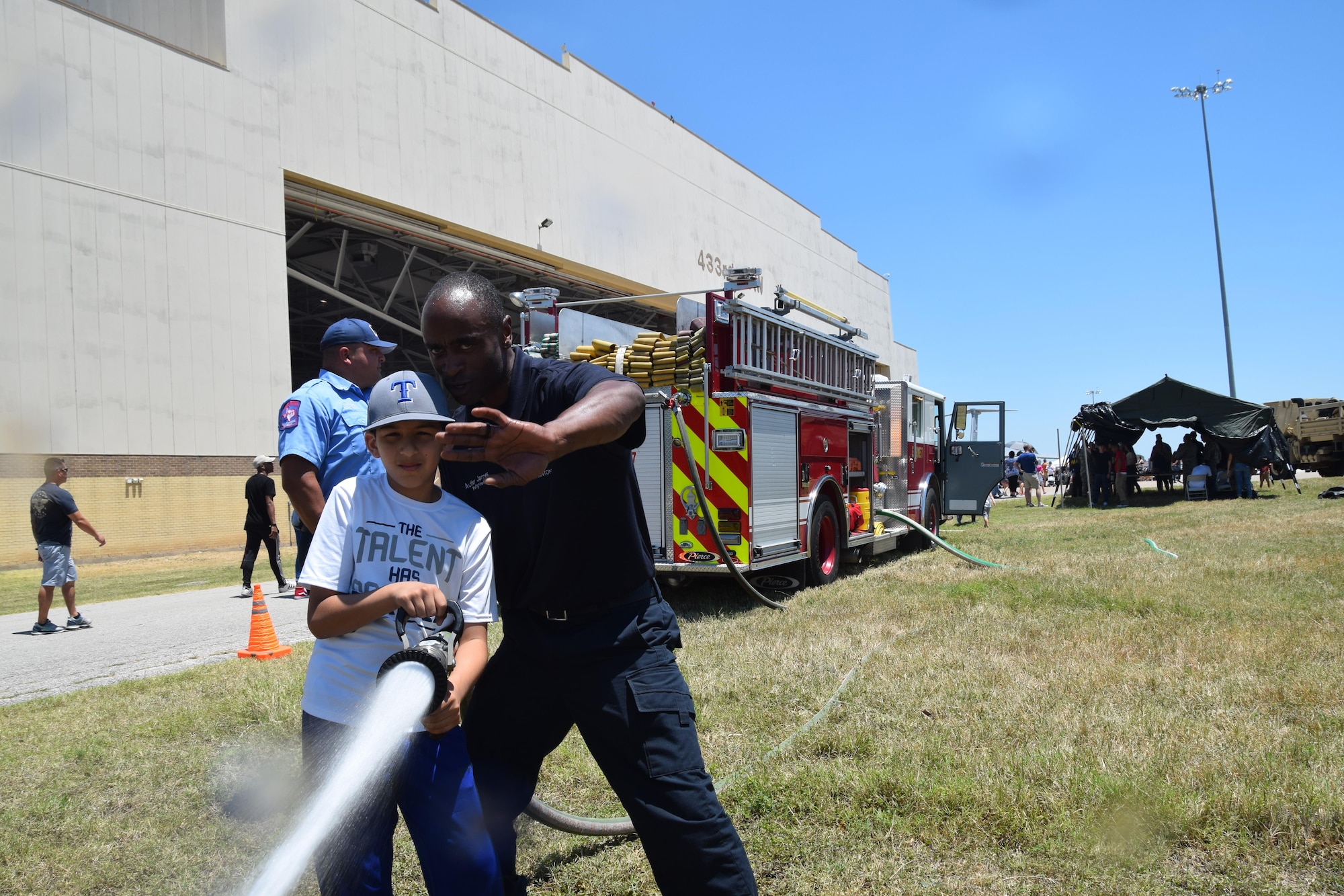 Eden Alvarado uses a fire hose under the direction of Author James, a 502nd Civil Engineering Squadron firefighter, at the 433rd Airlift Wing’s Family Day May 7, 2017 at Joint Base San Antonio-Lackland, Texas.  Alvarado is the stepson of Master Sgt. Brian Gray, 433rd Maintenance Squadron. (U.S. Air Force photo by Tech. Sgt. Carlos J. Trevino)