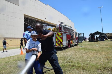 Eden Alvarado uses a fire hose under the direction of Author James, a 502nd Civil Engineering Squadron firefighter, at the 433rd Airlift Wing’s Family Day May 7, 2017 at Joint Base San Antonio-Lackland, Texas.  Alvarado is the stepson of Master Sgt. Brian Gray, 433rd Maintenance Squadron. (U.S. Air Force photo by Tech. Sgt. Carlos J. Trevino)