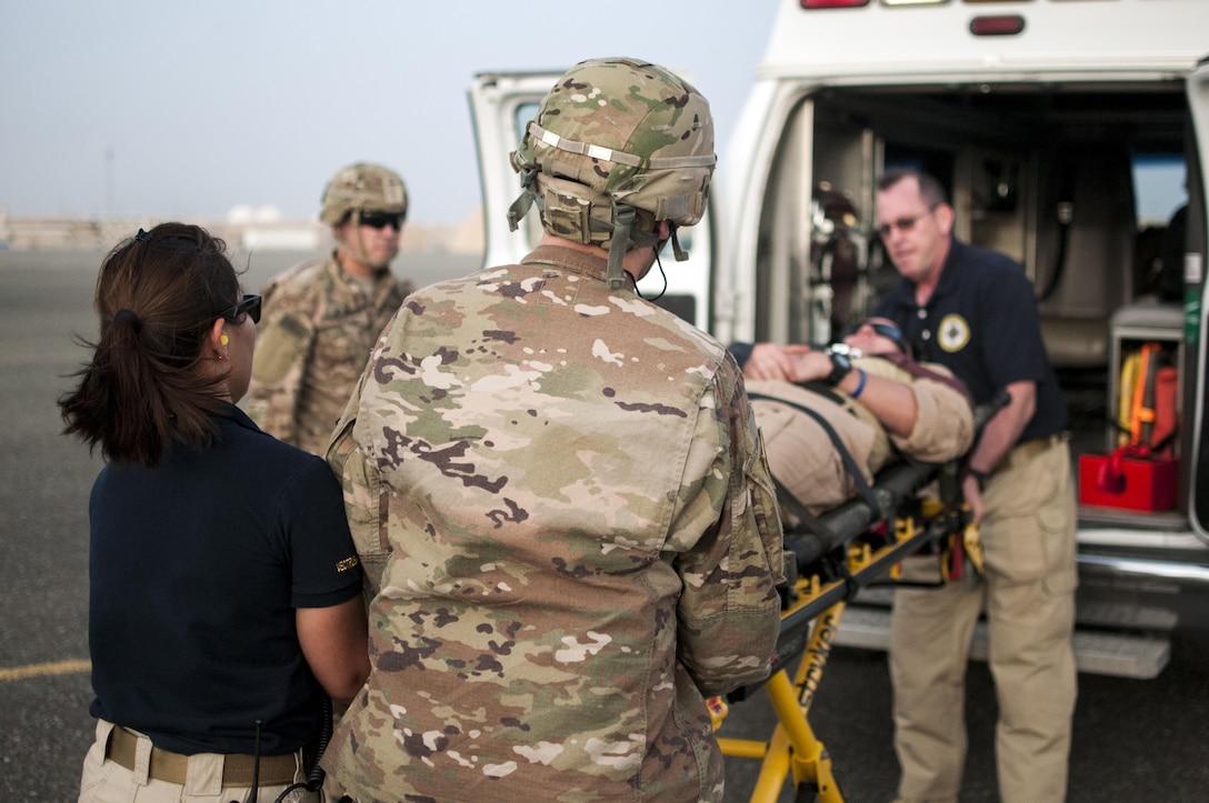 U.S. Army combat medics, with the 86th Combat Support Hospital, and Emergency Medical Technicians, with Area Support Group - Kuwait, Joint Emergency Service, move a simulated casualty onto an ambulance, during a joint training exercise with Marines from Marine Medium Tiltrotor Squadron - 364 (VMM-364), at Camp Arifjan, Kuwait, May 8, 2017. (U.S. Army Photo by Sgt. Christopher Bigelow)