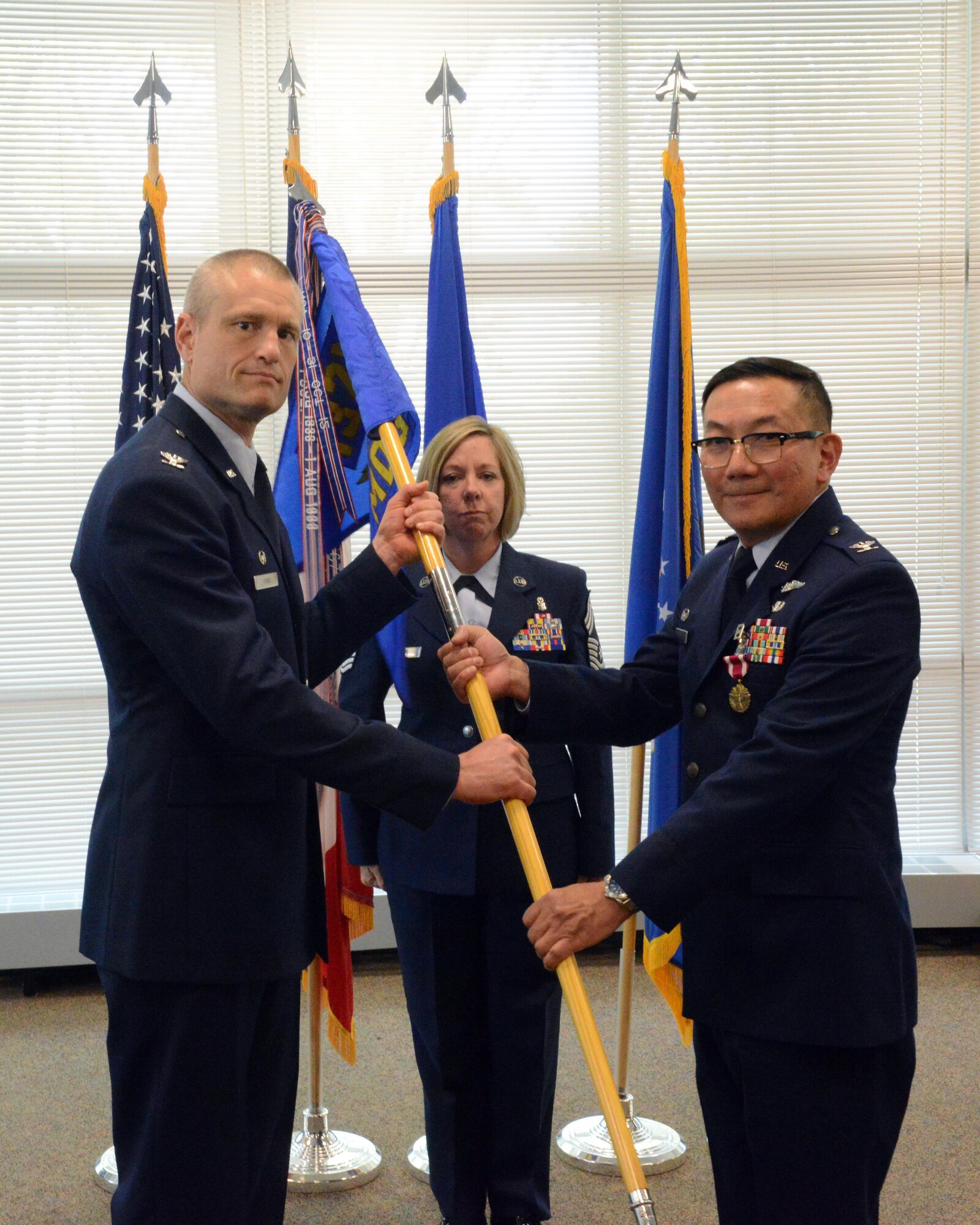 Col. Jim P. Duong (right), 132d Wing (132 WG) outgoing Medical Group (MDG) commander and Col. Shawn D. Ford (left), commander 132 WG, pose for a photo during the exchange of the 132 WG MDG guidon during the change of command ceremony at the 132 WG MDG, Des Moines, Iowa on May 7, 2017. This action formally recognized Duong passing over the MDG commander role, where he served for five years. (U.S. Air National Guard photo by Airman 1st Class Katelyn Sprott)