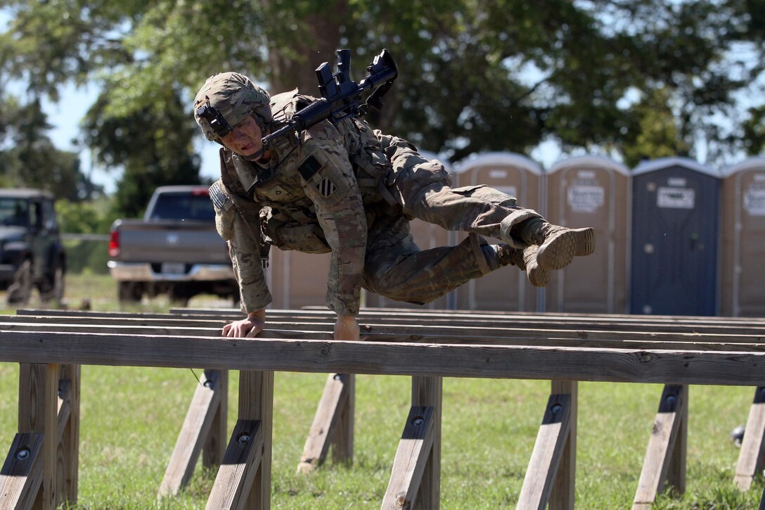 Army Pfc. Matthew Bates, a cavalry scout with the 3rd Infantry Division squad at the Gainey Cup competition, jumps over an obstacle during a stress shoot event at Fort Benning, Ga., May 2, 2017. Army photo by Staff Sgt. Candace Mundt