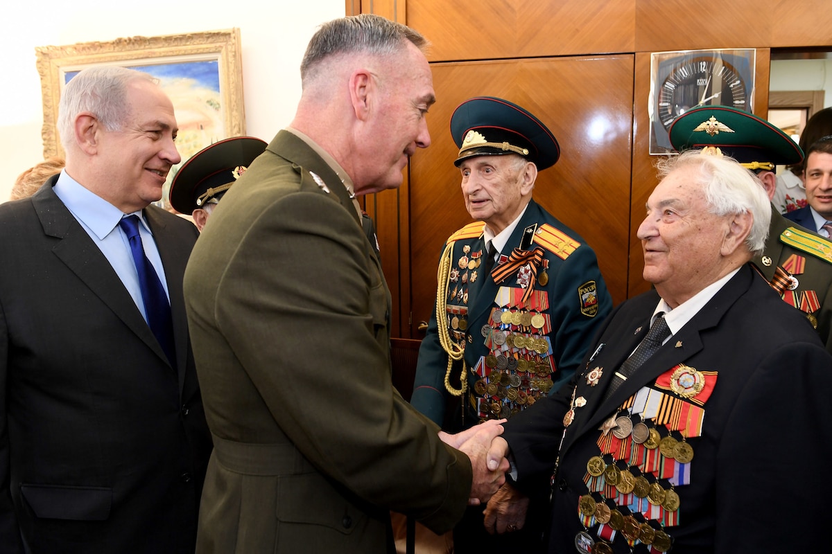 Marine Corps Gen. Joe Dunford, chairman of the Joint Chiefs of Staff, shakes hands with a veteran wearing medals.