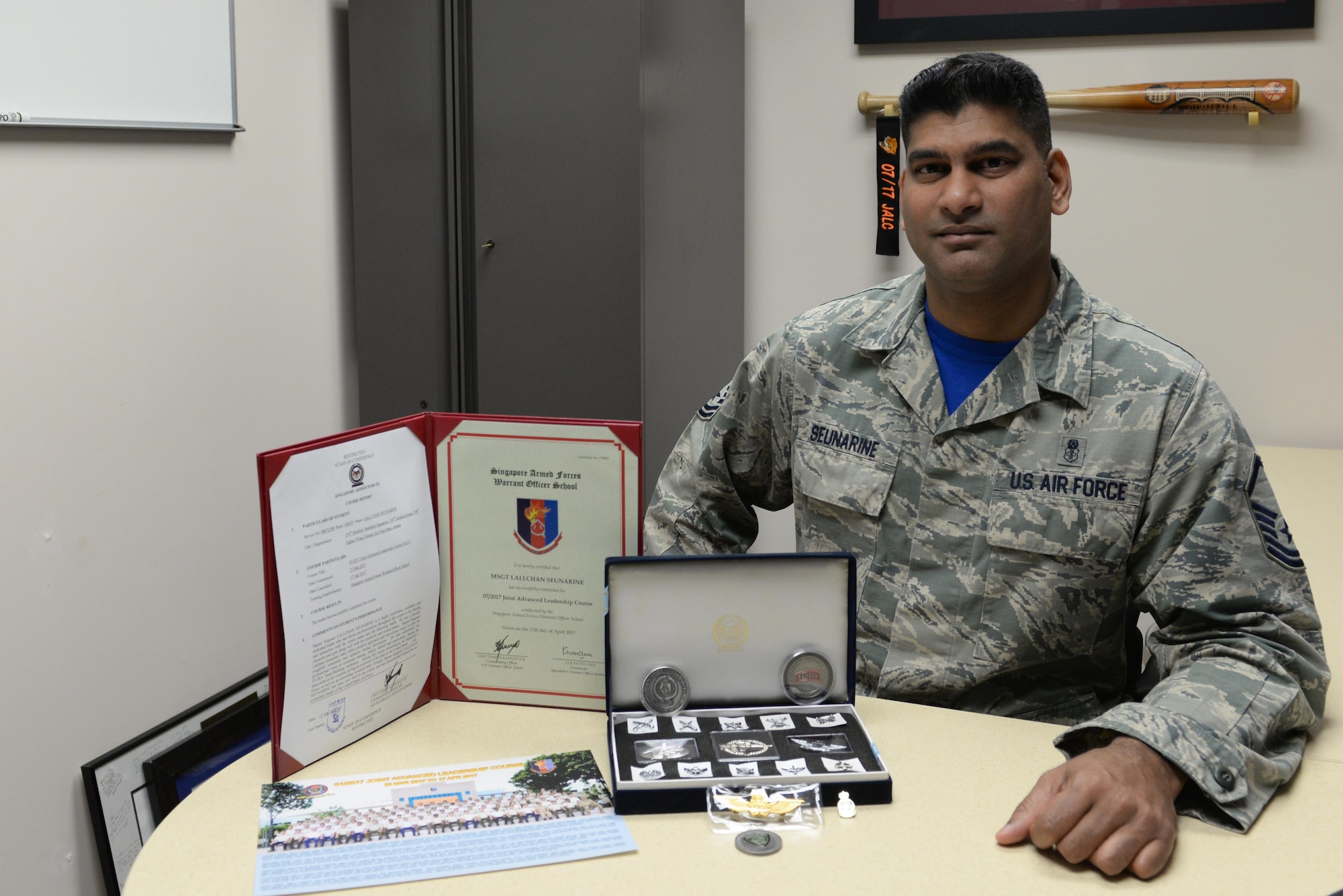 U.S. Air Force Master Sgt. Lallchan Seunarine, the 354th Medical Operations Squadron public health flight chief, poses with items from the Singapore Enlisted Officer Training Course May 5, 2017, at Eielson Air Force Base, Alaska. Seunarine’s syndicate team presented him with several items to memorialize their time learning together. (U.S. Air Force photo by Airman 1st Class Cassandra Whitman)
