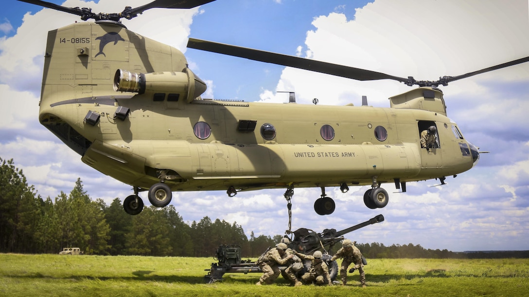 Soldiers maneuver after attaching an M119A3 howitzer to the belly of an CH-47F Chinook helicopter during slingload operations at Fort Bragg, N.C., May 4, 2017. The soldiers are assigned to the 82nd Airborne Division's 1st Battalion, 319th Airborne Field Artillery Regiment. The helicopter is assigned to 3rd General Support Aviation Battalion, 82nd Combat Aviation Brigade. Army photo by Sgt. Steven Galimore