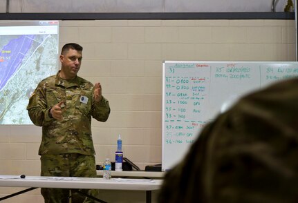 U.S. Army Reserve Maj. William Moss, the shift officer in charge for Task Force 76 out of Westover, Mass., conducts a battle rhythm brief during Vibrant Response 17 at Camp Atterbury, Ind., May 7, 2017. Vibrant Response 17 is an annual command post exercise that simulates the detonation of a nuclear bomb in a major city within the United States. This year it was integrated with Guardian Response 17 at Muscatatuck Urban Training Center, Indiana. The exercises enable emergency response organizations, both civilian and military, to integrate and provide relief during a catastrophic disaster. (U.S. Army Reserve Photo by Sgt. Stephanie Ramirez)