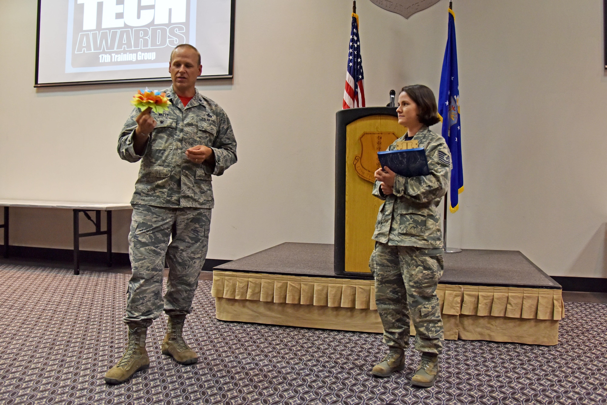 U.S. Air Force Lt. Col. Steven Watts II, 17th Training Group Deputy Commander, asks Tech. Sgt. Cheyanne Samples, 315th Training Squadron instructor, about the paper flower she used in the Top Tech competition at the Event Center on Goodfellow Air Force Base, Texas, May 5, 2017. Watts announced Samples as the best instructor of the 17th TRG for the first quarter. During the competition, instructors had to teach a subject and audience members had to demonstrate their understanding of the topic. (U.S. Air Force photo by Staff Sgt. Joshua Edwards/Released)