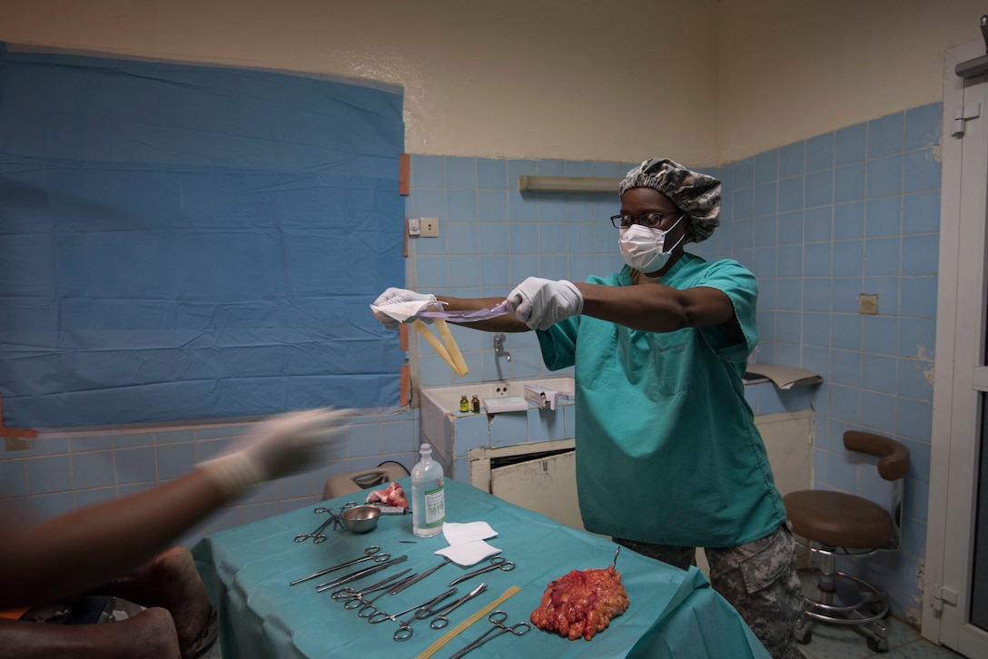 U.S. Army Reserve Sgt. Nykita Williams, an operating room technician, provides a sterile drain during an excision of back lipoma surgery during Medical Readiness Training Exercise 17-3 at the Military Teaching Hospital in N'Djamena, Chad, May 4. The mutually beneficial exercise offers opportunities for the partnered militaries to share best practices and improve medical treatment processes. (U.S. Army Africa photo by Staff Sgt. Shejal Pulivarti)