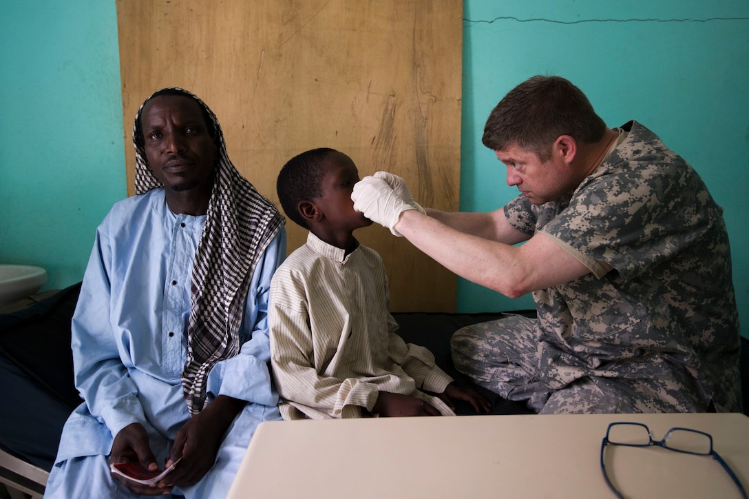 U.S. Army Reserve Col. Peter Ray, a pediatric plastics and reconstructive surgeon, assigned to 3rd Medical Command Deployment Support in Forest Park, Ga., examines Owmar Aima with his father present during Medical Readiness Training Exercise 17-3 at the Military Teaching Hospital in N'Djamena, Chad, May 5. The partnered medical equipment technicians will perform diagnostic tests and repair nonfunctional medical equipment. The mutually beneficial exercise offers opportunities for the partnered militaries to share best practices and improve medical treatment processes. (U.S. Army Africa photo by Staff Sgt. Shejal Pulivarti)
