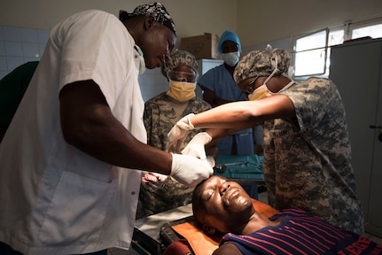 Chadian Capt. Dillah Naiwallah, an instrument supervisor, U.S. Army Reserve Sgts. Talithia Williams and Nykita Williams, both operating room technicians, assigned to 3rd Medical Command Deployment Support in Forest Park, Ga., suture a scalp laceration due to a gunshot wound during Medical Readiness Training Exercise 17-3 at the Military Teaching Hospital in N'Djamena, Chad, May 4. The mutually beneficial exercise offers opportunities for the partnered militaries to share best practices and improve medical treatment processes. (U.S. Army Africa photo by Staff Sgt. Shejal Pulivarti)