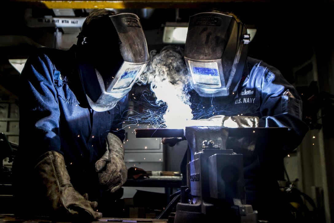 Navy Petty Officer 2nd Class Sarah Benner and Petty Officer 3rd Class Corinne Gharineh weld in the machine shop of the USS Pearl Harbor in the Pacific Ocean, May 7, 2017. Navy photo by Petty Officer 3rd Class Tarra Samoluk