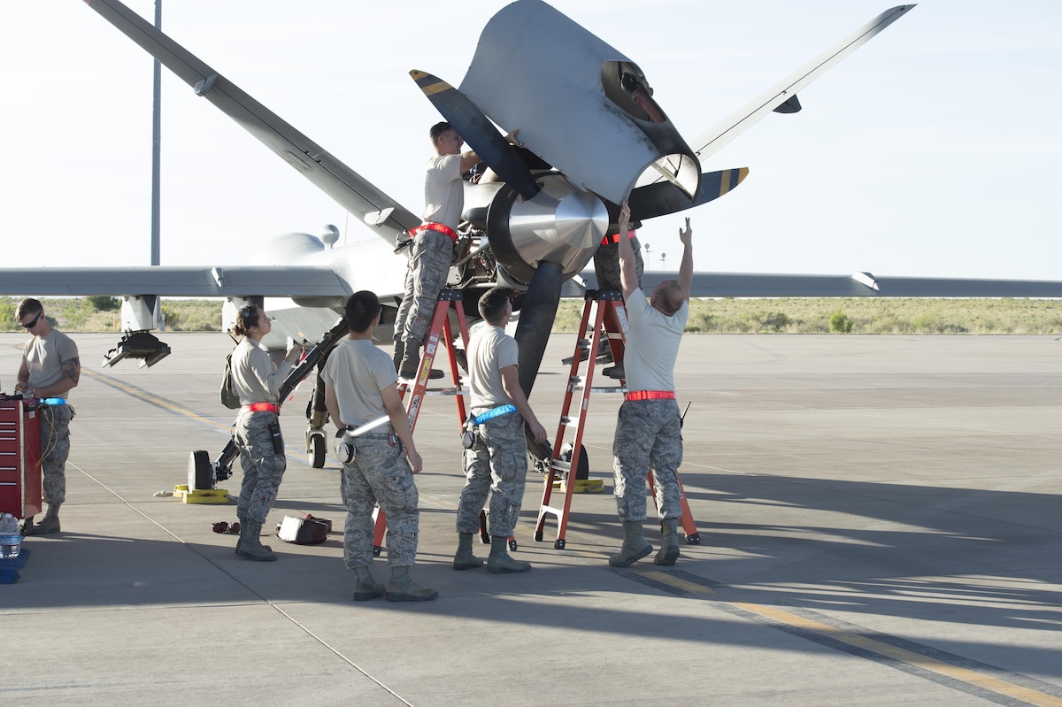 49th Aircraft Maintenance squadron Airmen hoist an engine cover panel onto an MQ-9 at Holloman Air Force Base, N.M., May 4, 2017. Holloman AFB conducted surge operations from May 1 to May 5, ramping up operations to accurately measure the full capability of its Airmen and equipment. 