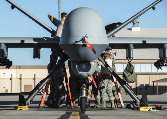 49th Aircraft Maintenance squadron Airmen hoist an engine cover panel onto an MQ-9 at Holloman Air Force Base, N.M., May 4, 2017. Holloman AFB conducted surge operations from May 1 to May 5, ramping up operations to accurately measure the full capability of its Airmen and equipment.(U.S. Air Force photo by Senior Airman Chase Cannon)