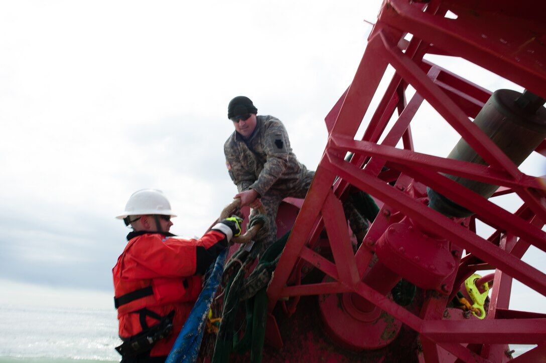 Coast Guard Chief Warrant Officer Benjamin Jewell, assigned to the Cutter Oak; and Sgt. 1st Class Chris Richards, assigned to the Connecticut Army National Guard prepare a 12,000-pound beached buoy to be lifted by a CH-47 Chinook helicopter near Chatham, Mass., May 9, 2017. The buoy was brought offshore where it was picked up by the Cutter Oak, a 225-foot Coast Guard buoy tender homeported in Newport, R.I.. Coast Guard photo by Petty Officer 3rd Class Andrew Barresi