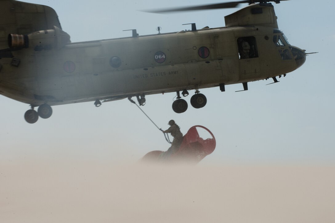 Connecticut Army National Guard Sgt. 1st Class Chris Richards attaches a 12,000-pound beached buoy to a CH-47 Chinook helicopter near Chatham, Mass., May 9, 2017. The Chinook lifted the buoy from the beach and brought it offshore where the Coast Guard Cutter Oak picked it up. Coast Guard photo by Petty Officer 3rd Class Andrew Barresi