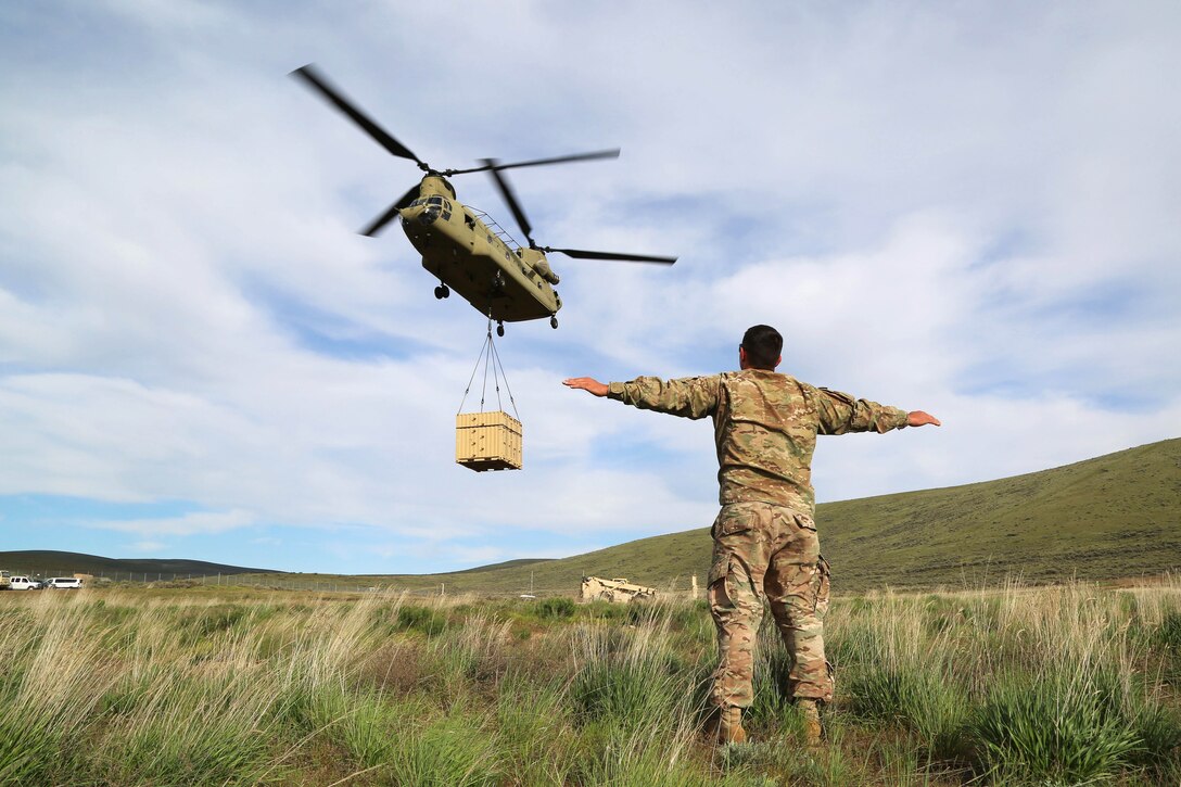 Army Staff Sgt. Keith Beardsley signals a CH-47 Chinook helicopter to hover during a slingload operation, part of Exercise Dragon Fire, at the Yakima Training Center, Yakima, Wash., May 5, 2017. Beardsley is an air assault instructor from the Phantom Warrior Academy. Army photo by Sgt. Kalie Jones