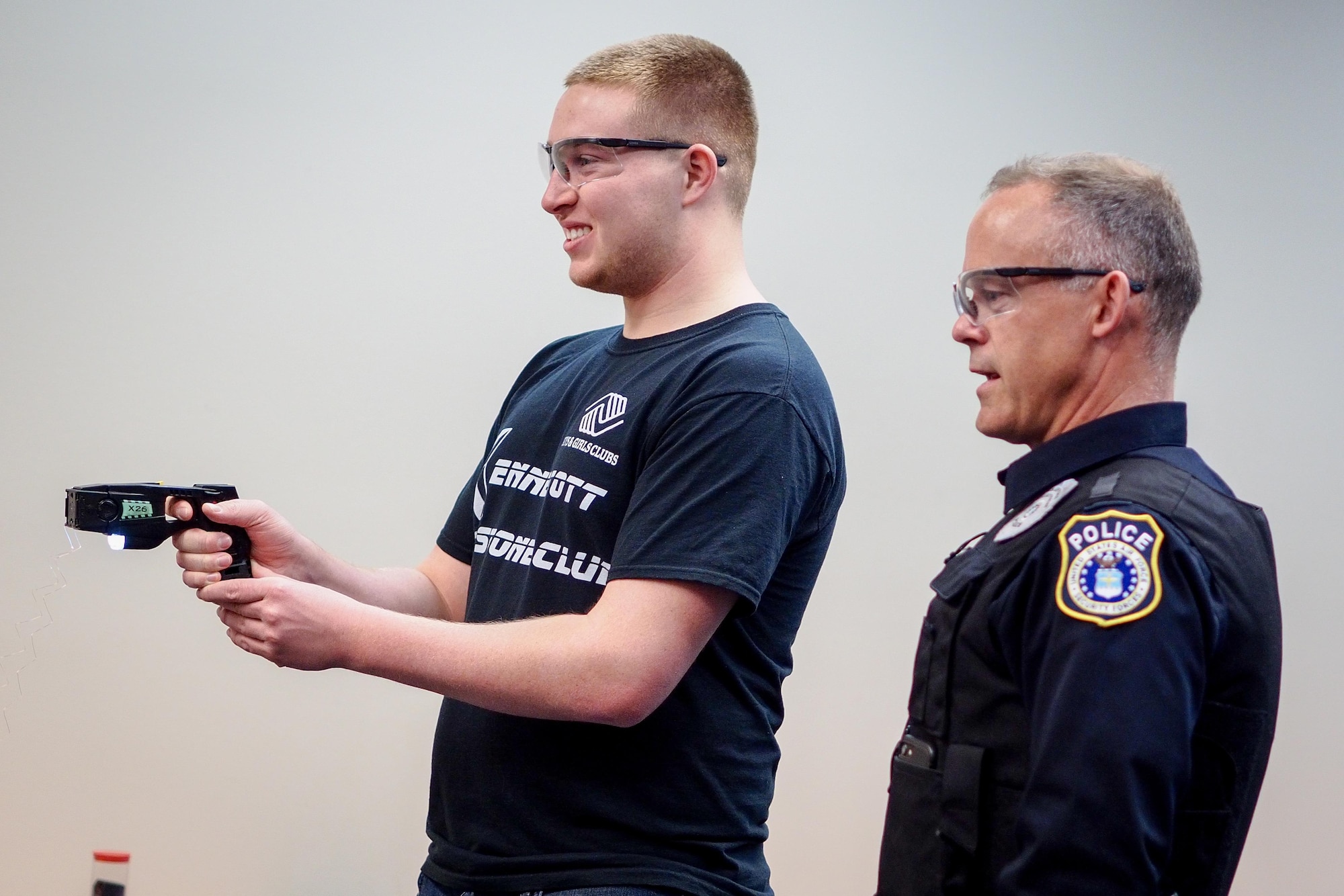 Aaron Regevig, Bartlett High School student, fires a taser while Officer Scott Garner, Joint Base Elmendorf-Richardson civilian police officer trainer, watches during a job-shadowing program, May 4, 2017. The program is geared toward high school students who want to explore a career field. (U.S. Air Force photo/Justin Connaher)