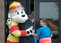 Sparky the Fire Dog, 5th Civil Engineer Squadron fire prevention educator, greets Edison Elementary School’s science, technology, engineering and math girls at the 5th CES fire station on Minot Air Force Base, N.D., May 1, 2017. During the STEM girls’ visit to the fire station, Sparky taught them about fire safety and basic firefighter duties. (U.S. Air Force photo/Airman 1st Class Alyssa M. Akers)