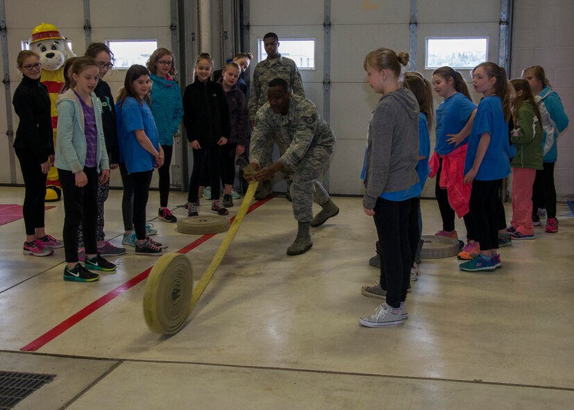Staff Sgt. Shawn Vrock, 5th Civil Engineer Squadron crew chief, rolls a hose at the 5th CES fire station on Minot Air Force Base, N.D., May 1, 2017. Edison Elementary School’s science, technology, engineering and math girls received a firehouse tour and learned basic firefighter duties. (U.S. Air Force photo/Airman 1st Class Alyssa M. Akers)