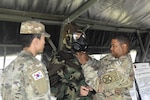 Staff Sgt. Joseph Brown, Headquarters and Headquarters Company, United States Army Garrison Daegu, demonstrates how to properly wear protective mask at Camp Henry on Apr. 24. 

