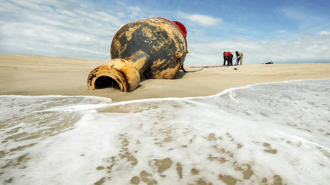Connecticut Army National Guard Sgt. 1st Class Chris Richards, Coast Guard Chief Warrant Officer Benjamin Jewell and Petty Officer 3rd Class Andrew Hayden prepare a sling to hoist a 12,000-pound beached buoy near Chatham, Mass., May 9, 2017. The buoy broke free of its mooring off the coast of Maine during a winter storm. Coast Guard photo by Petty Officer 3rd Class Andrew Barresi