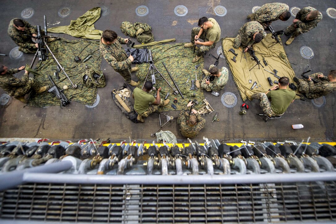 Marines clean weapons in the well deck of the USS Pearl Harbor in the Pacific Ocean, May 6, 2017. The Marines are assigned to the 15th Marine Expeditionary Unit. Navy photo by Petty Officer 3rd Class Tarra Samoluk