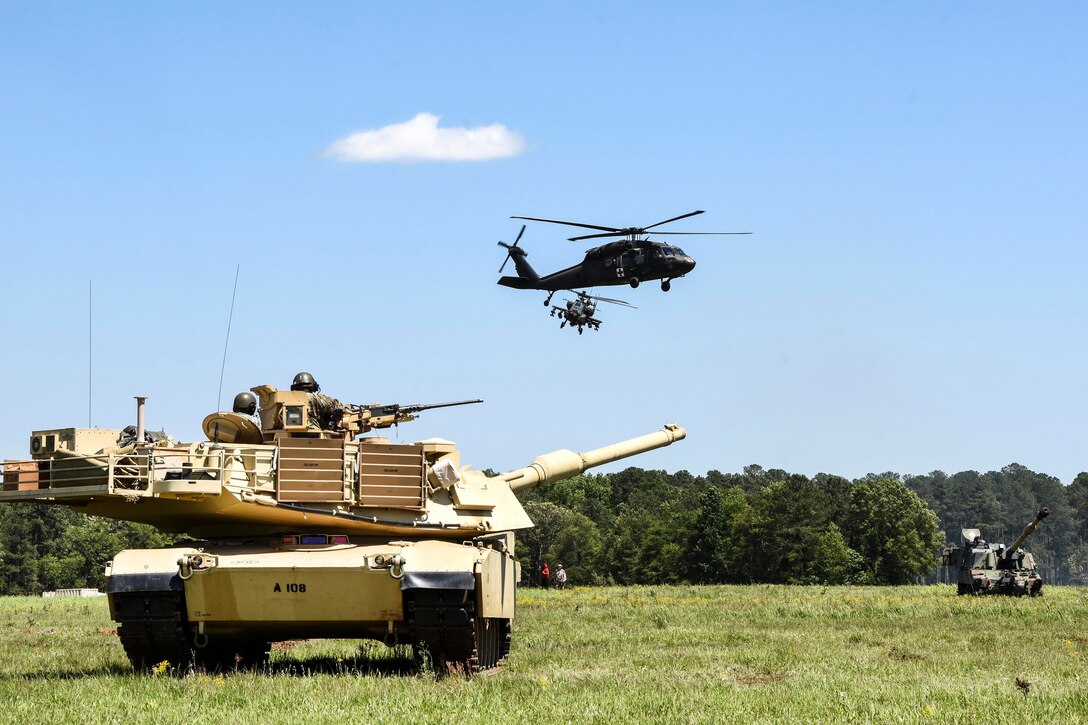 A UH-60 Black Hawk and AH-64 Apache attack helicopter fly over an M1A2 Abrams main battle tank providing firepower while participating in a Combined Arms Demonstration during the South Carolina National Guard Air and Ground Expo at McEntire Joint National Guard Base, S.C., May 6, 2017. The expo showcases South Carolina National Guard airmen and soldiers. Army National Guard photo by Sgt. Tashera Pravato